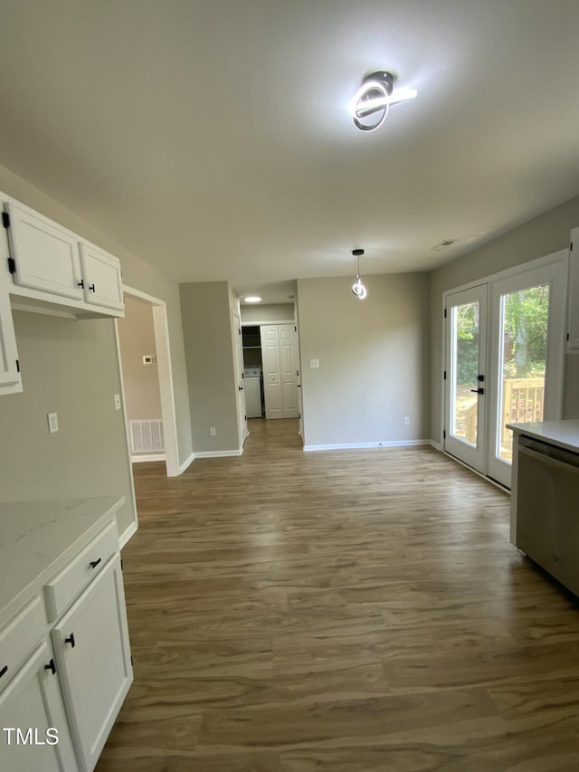 unfurnished dining area featuring french doors, baseboards, visible vents, and wood finished floors