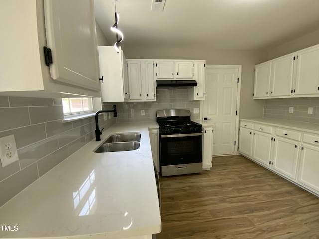 kitchen featuring a sink, stainless steel gas range oven, white cabinetry, decorative backsplash, and under cabinet range hood