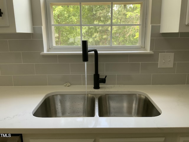 details featuring backsplash, white cabinetry, and a sink