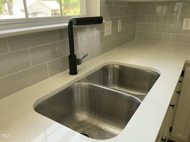 interior details featuring white cabinetry, decorative backsplash, and a sink
