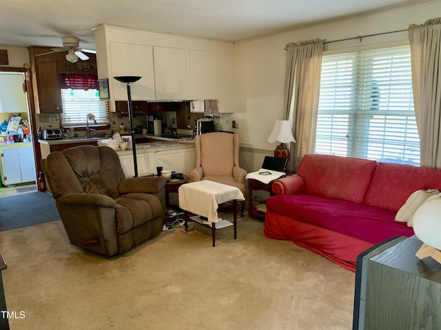 living area featuring a ceiling fan, a healthy amount of sunlight, and light carpet