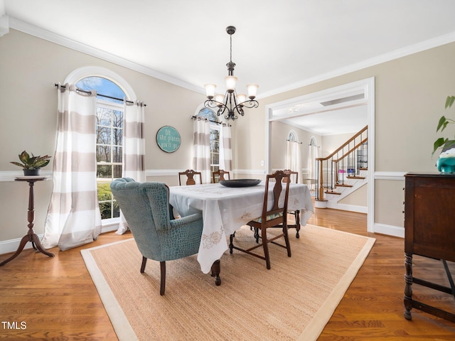 dining space with an inviting chandelier, light wood-style flooring, stairs, and ornamental molding