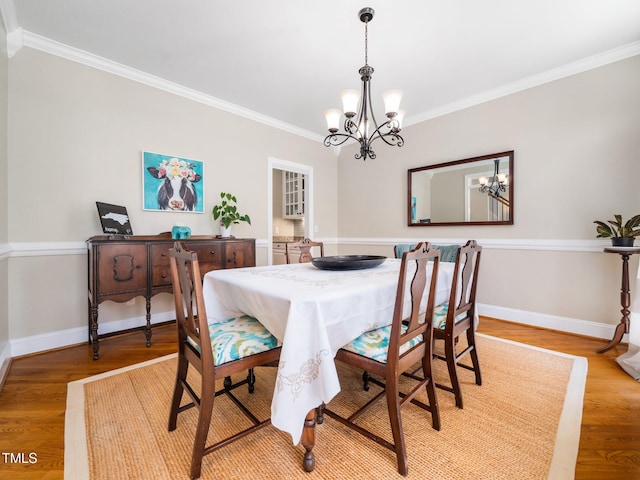 dining area with light wood finished floors, a notable chandelier, baseboards, and ornamental molding