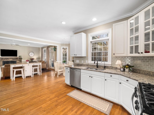 kitchen with a sink, open floor plan, white cabinetry, light wood-style floors, and appliances with stainless steel finishes