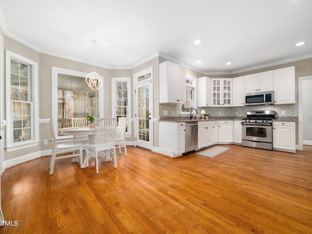 kitchen featuring decorative backsplash, white cabinets, appliances with stainless steel finishes, and a sink