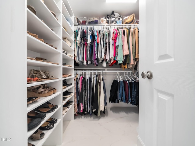 walk in closet featuring marble finish floor