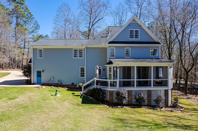 rear view of property with a lawn and a sunroom