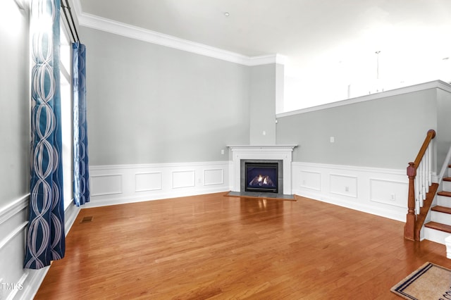 living room featuring visible vents, a fireplace with flush hearth, stairway, wood finished floors, and crown molding