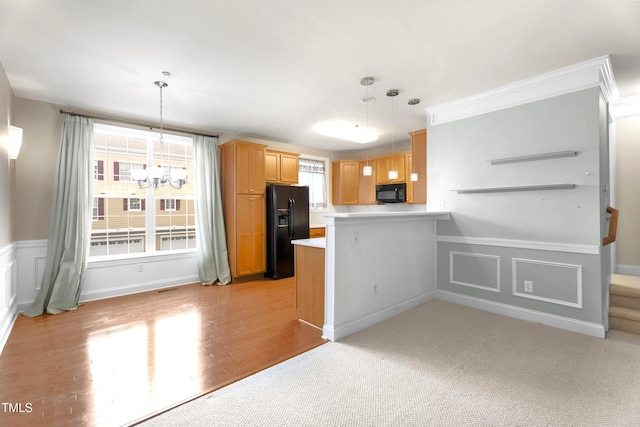 kitchen featuring decorative light fixtures, light countertops, a chandelier, a peninsula, and black appliances