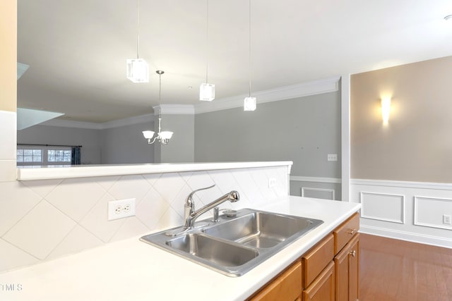 kitchen with ornamental molding, light countertops, a sink, and wood finished floors