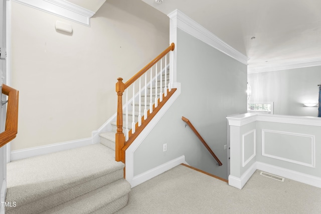 staircase featuring carpet floors, baseboards, visible vents, and crown molding