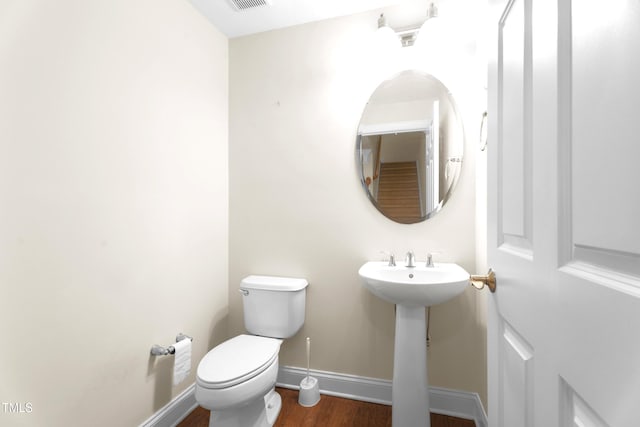 bathroom featuring visible vents, toilet, a sink, wood finished floors, and baseboards