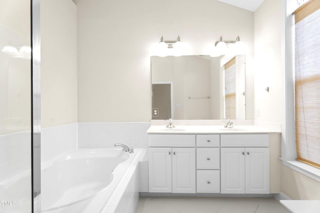 bathroom with double vanity, a garden tub, a sink, and tile patterned floors