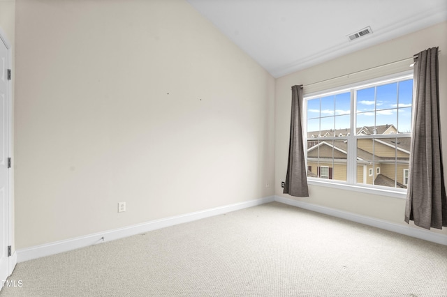 carpeted empty room featuring lofted ceiling, visible vents, and baseboards