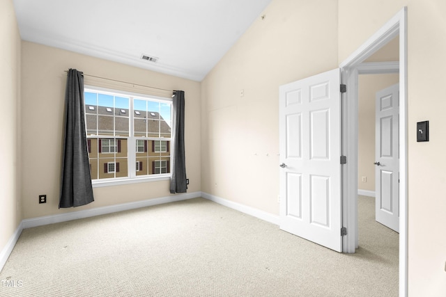 empty room featuring carpet floors, baseboards, visible vents, and lofted ceiling