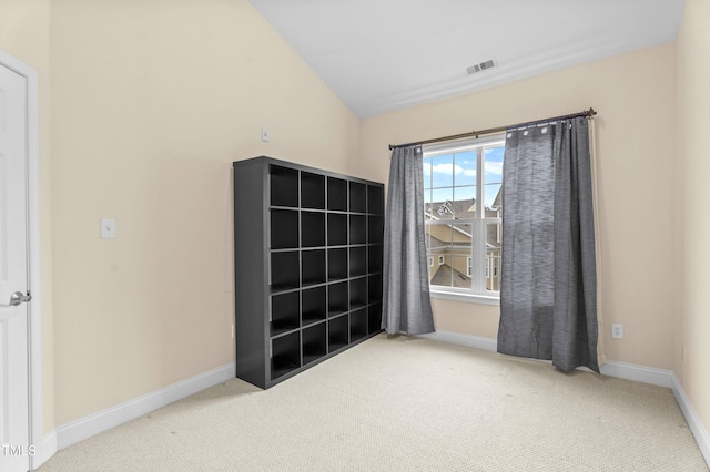 carpeted empty room featuring vaulted ceiling, visible vents, and baseboards