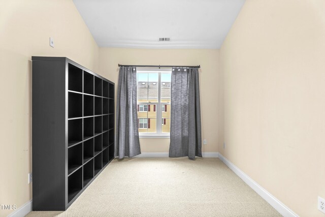 carpeted spare room with visible vents and baseboards