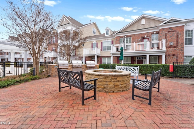 view of patio / terrace with an outdoor fire pit, a grill, fence, and exterior kitchen