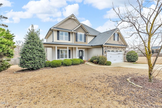 craftsman inspired home with driveway, a garage, stone siding, fence, and board and batten siding