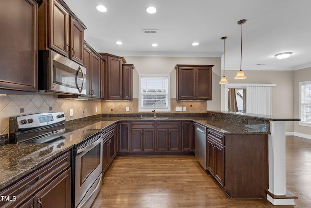 kitchen featuring stainless steel appliances, visible vents, a sink, plenty of natural light, and a peninsula