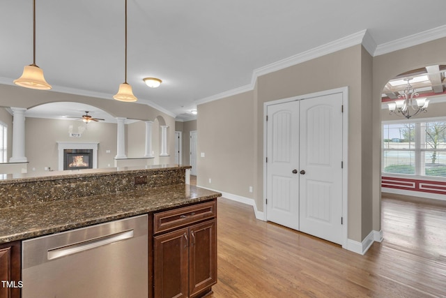 kitchen featuring decorative columns, arched walkways, a glass covered fireplace, light wood-style flooring, and stainless steel dishwasher