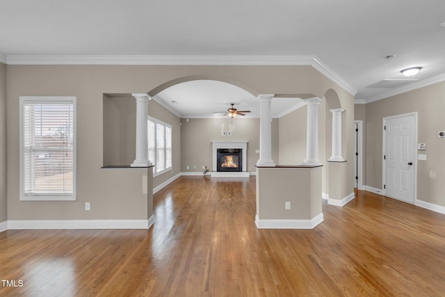 unfurnished living room with decorative columns, ceiling fan, wood finished floors, and a glass covered fireplace