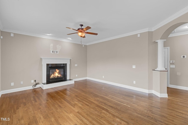 unfurnished living room with decorative columns, arched walkways, ceiling fan, and wood finished floors