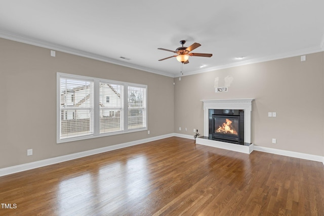 unfurnished living room featuring baseboards, wood finished floors, a glass covered fireplace, and crown molding