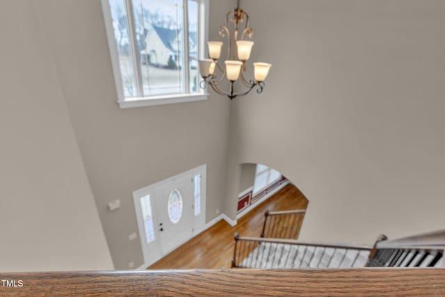 entryway featuring arched walkways, wood finished floors, and an inviting chandelier