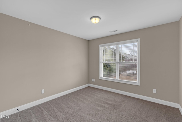 empty room featuring carpet floors, visible vents, and baseboards