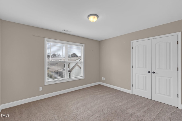 unfurnished bedroom with carpet, a closet, visible vents, and baseboards