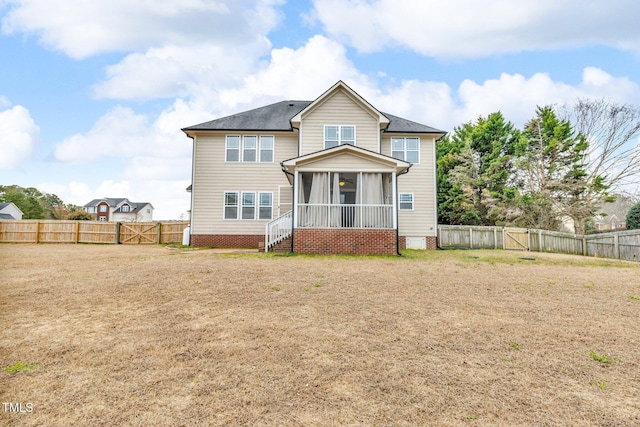 view of front of home with a front yard, a sunroom, a fenced backyard, and a gate