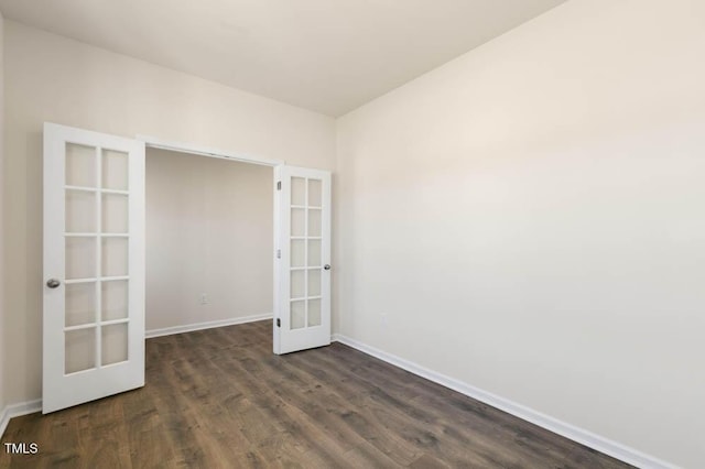 empty room with french doors, dark wood-style flooring, and baseboards