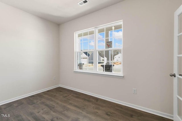 empty room featuring visible vents, dark wood finished floors, and baseboards