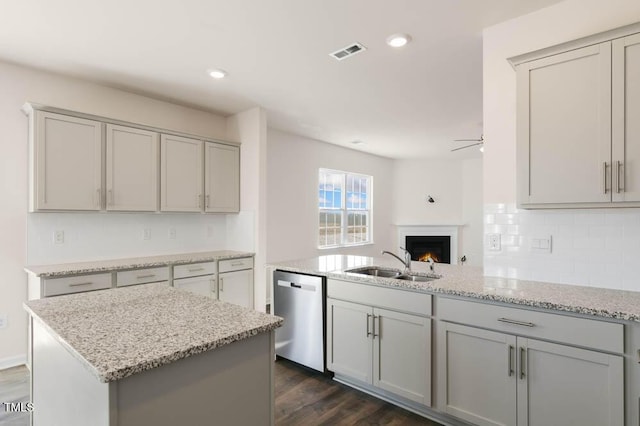 kitchen featuring visible vents, decorative backsplash, gray cabinetry, stainless steel dishwasher, and a sink