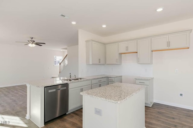 kitchen with a sink, light stone counters, dark wood finished floors, and dishwasher