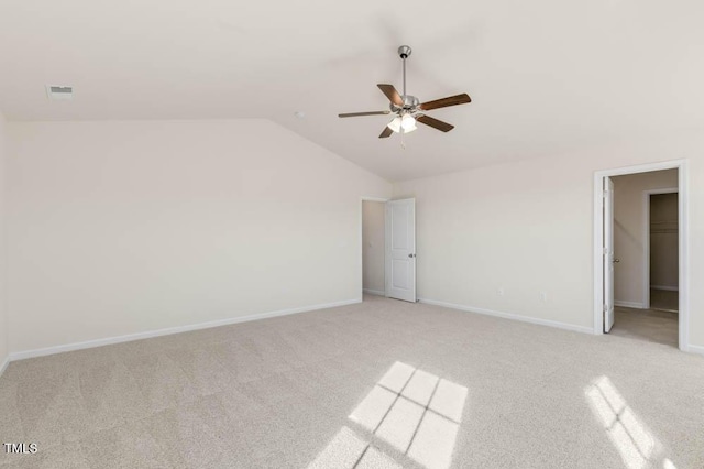 unfurnished room with baseboards, visible vents, vaulted ceiling, and light colored carpet