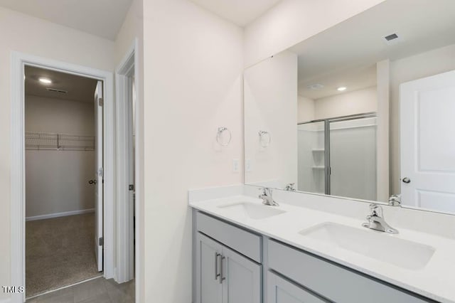 full bathroom featuring a spacious closet, double vanity, a sink, and visible vents