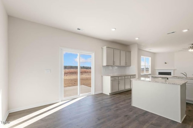 kitchen featuring dark wood-style floors, gray cabinets, open floor plan, a sink, and a kitchen island