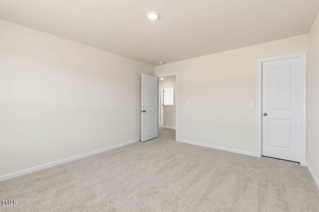 empty room featuring light colored carpet and baseboards