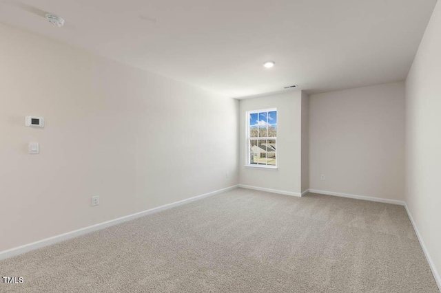 unfurnished room featuring baseboards and light colored carpet