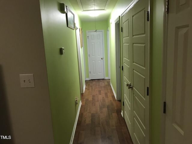 corridor featuring dark wood-style floors, attic access, and baseboards