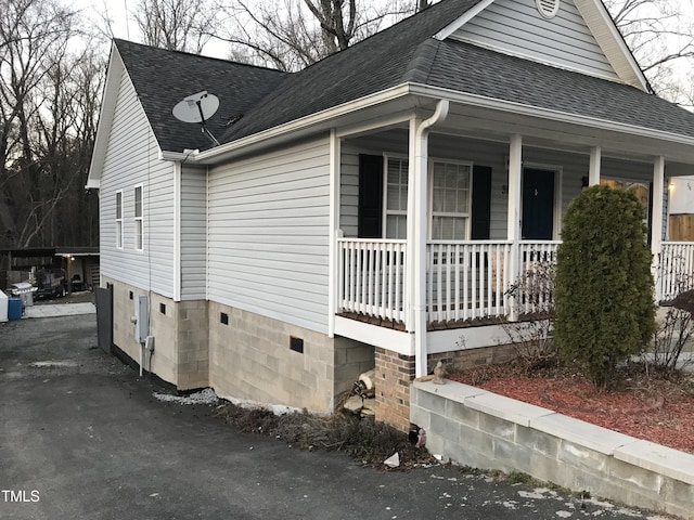 view of property exterior with a porch, crawl space, and roof with shingles