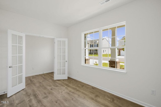 spare room with french doors, wood finished floors, visible vents, and baseboards