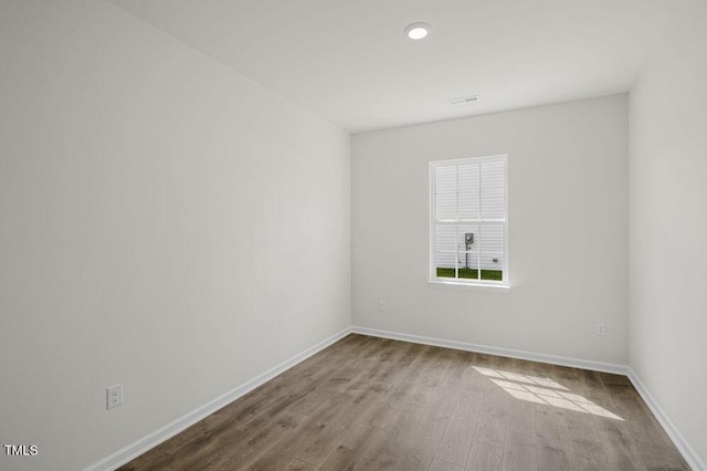 spare room with baseboards and wood finished floors