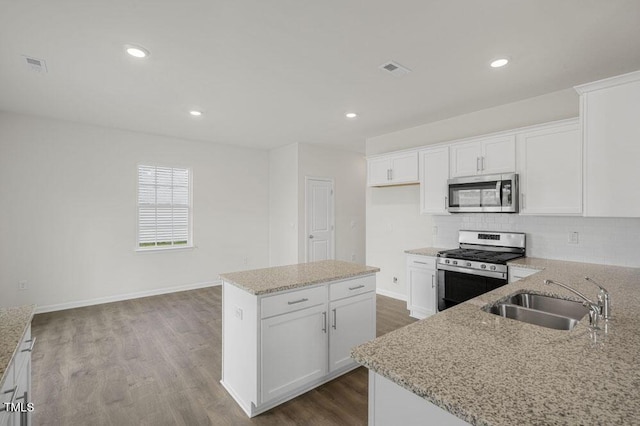 kitchen with tasteful backsplash, light stone counters, dark wood-type flooring, stainless steel appliances, and a sink