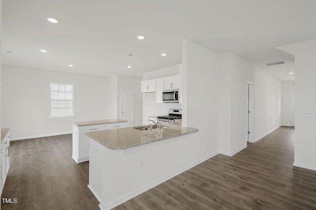 kitchen featuring dark wood-type flooring, visible vents, white cabinets, stainless steel microwave, and gas range