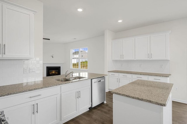 kitchen featuring dark wood-style floors, stainless steel dishwasher, a sink, and light stone countertops