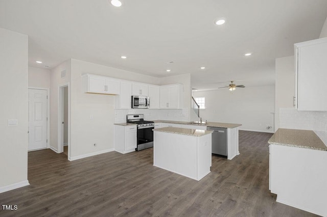 kitchen with stainless steel appliances, dark wood-type flooring, a peninsula, a kitchen island, and white cabinets