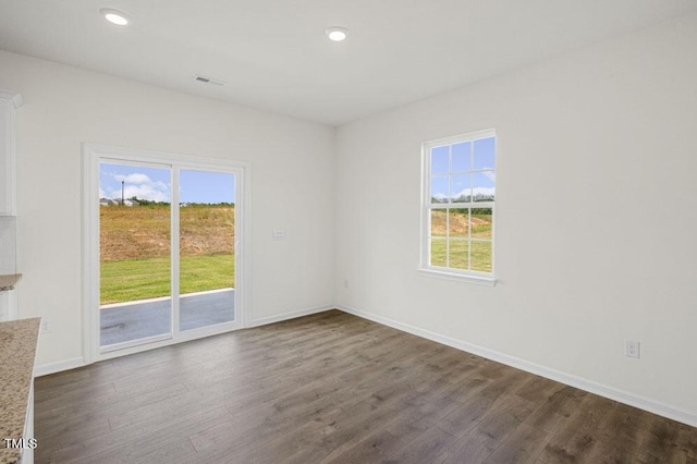 empty room with recessed lighting, dark wood-style flooring, visible vents, and baseboards